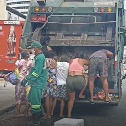 Pessoas famintas catam lixo de dentro do caminhão para comer