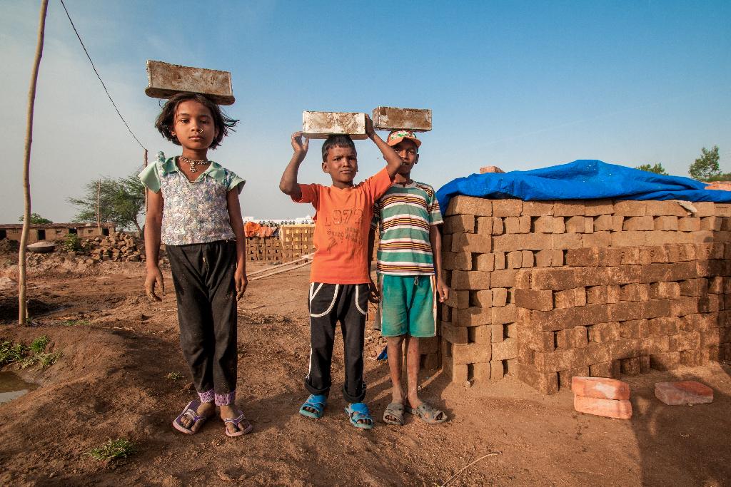 Crianças submetidas a trabalho infantil carregando tijolos na cabeça em fábrica de tijolos