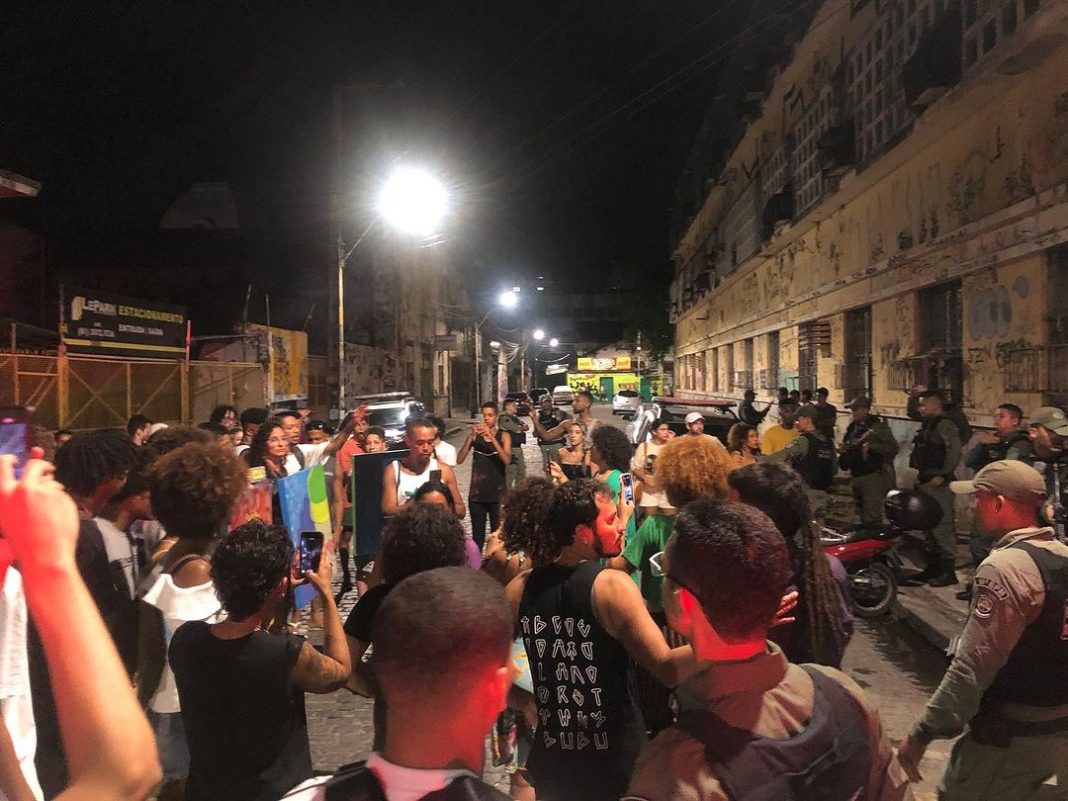 Momento em que a Mostra Coletiva de Arte Urbana foi interrompida pelos Policiais Militares do Recife. Na foto, há bastante gente, à noite, com iluminação dos postes.