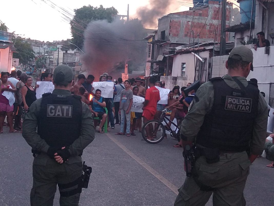 Manifestação por justiça pelo jovem Darik, no bairro do Jordão Baixo, Recife. Há a presença de dois policiais militares na imagem.