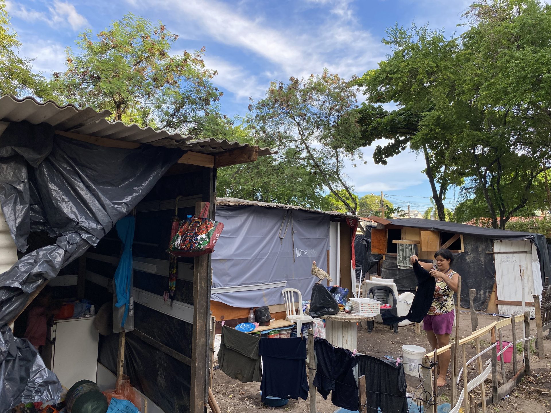 Moradora da Ocupação Ranúsia Alves estendendo roupas na frente de sua casa.