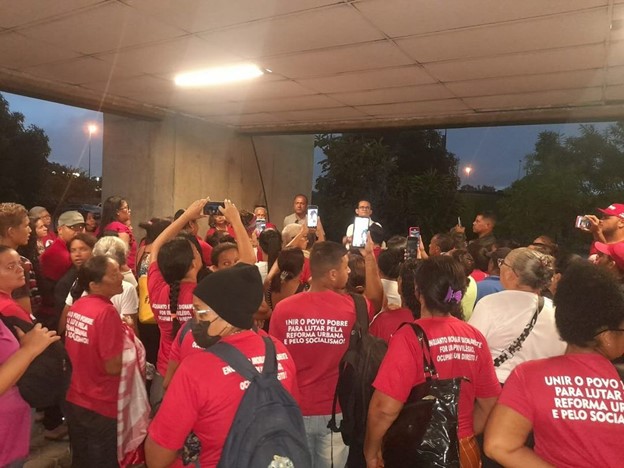 Movimento de Luta nos Bairros, Vilas e Favelas durante Assembleia de Reintegração de posse convocada pela Reitoria da UFPE. Militantes utilizam camisa vermelha com palavras de ordem do MLB.