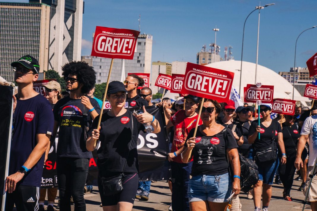 Pessoas com placa escrito greve durante manifestação da greve da educação federal em Brasília.