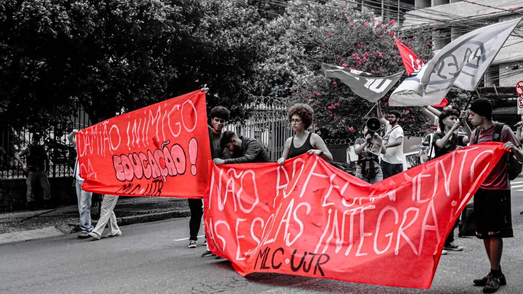 Manifestantes ocupam a rua em Belo Horizonte segurando faixas em defesa da educação pública e contra o fechamento de escolas