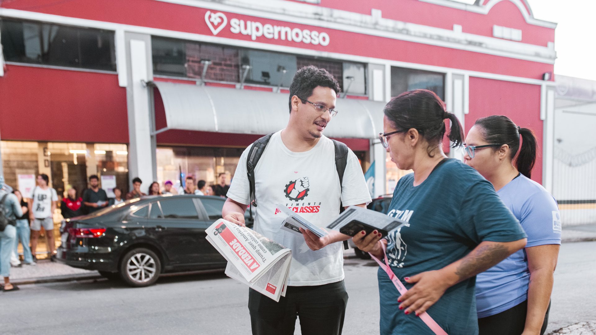 Militante do MLC entrega o jornal A Verdade para uma trabalhadora em frente ao mercado.